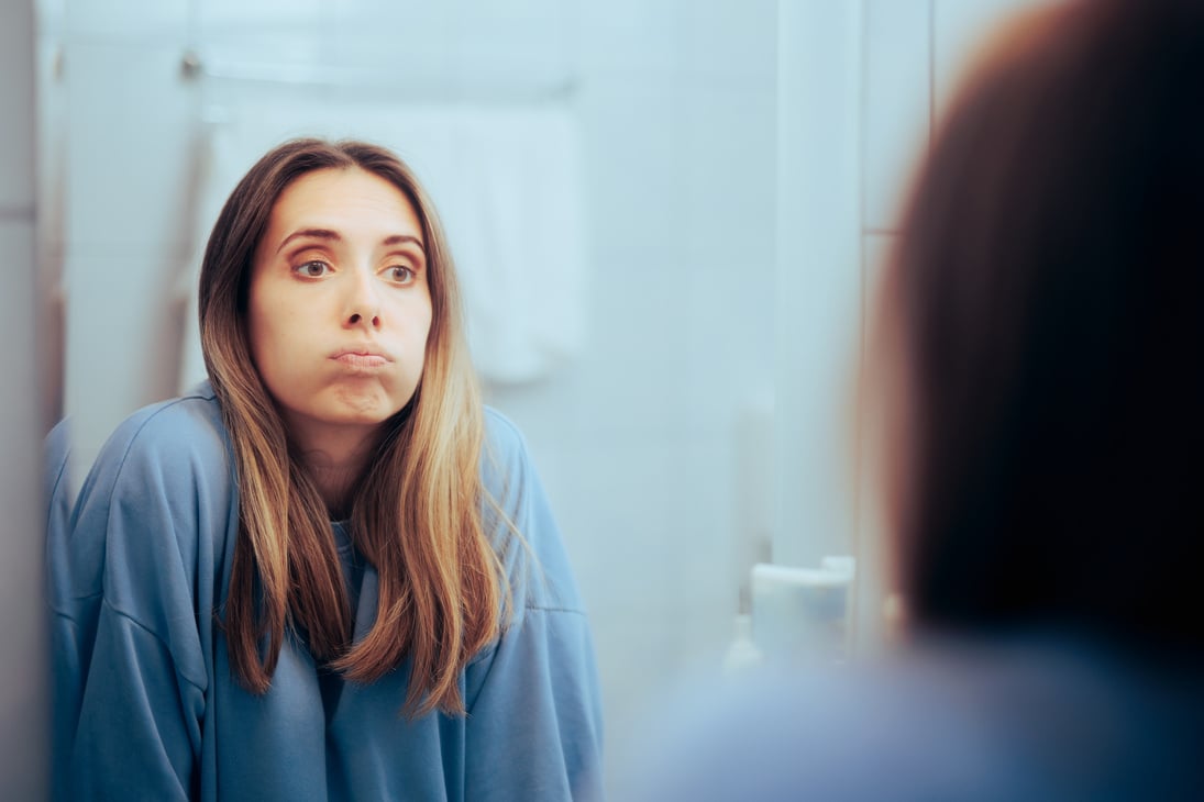 woman entrepreneur looking at herself in the mirror feeling overwhelmed by all the things she has to do for her business alone. 